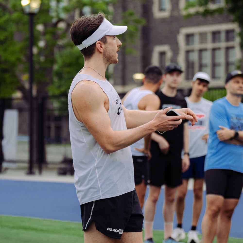 Man in athletic wear on a sports track with other people in the background
